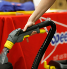 Person using a professional carpet cleaning machine at a Speedy Hire display.