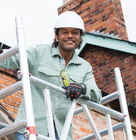 Person standing on scaffold tower cleaning house guttering