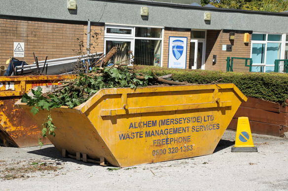 a yellow skip full of waste in an outdoor area