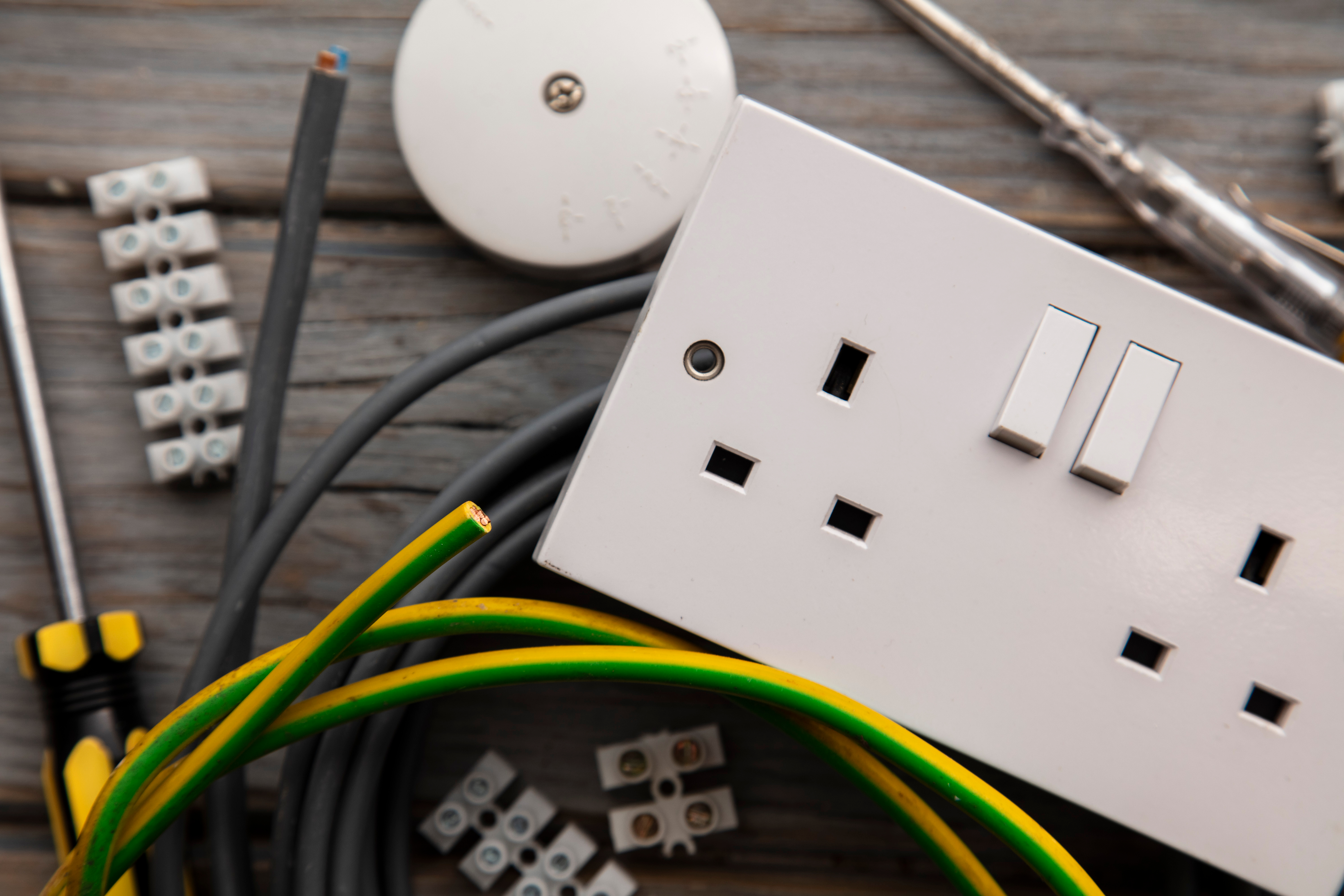Electrical socket with cables, connectors, and tools arranged on a wooden surface.