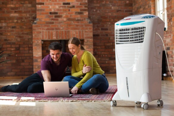 2 people sitting comfortably in a room using a white air conditioner