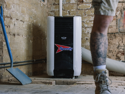 Portable air conditioner unit in a renovation space with exposed brick walls and tools nearby.