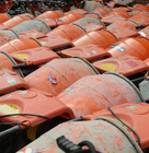 Rows of orange cement mixers arranged closely together, showing signs of wear and dried concrete splashes on their surfaces.