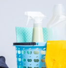 Cleaning supplies including spray bottle, gloves, and cloths in a blue basket