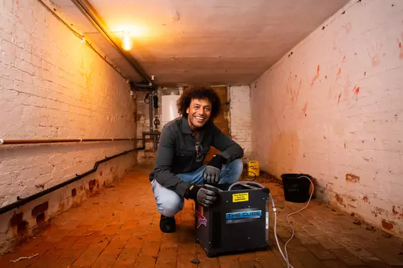 a man using the cube dehumidifier by Speedy in a basement