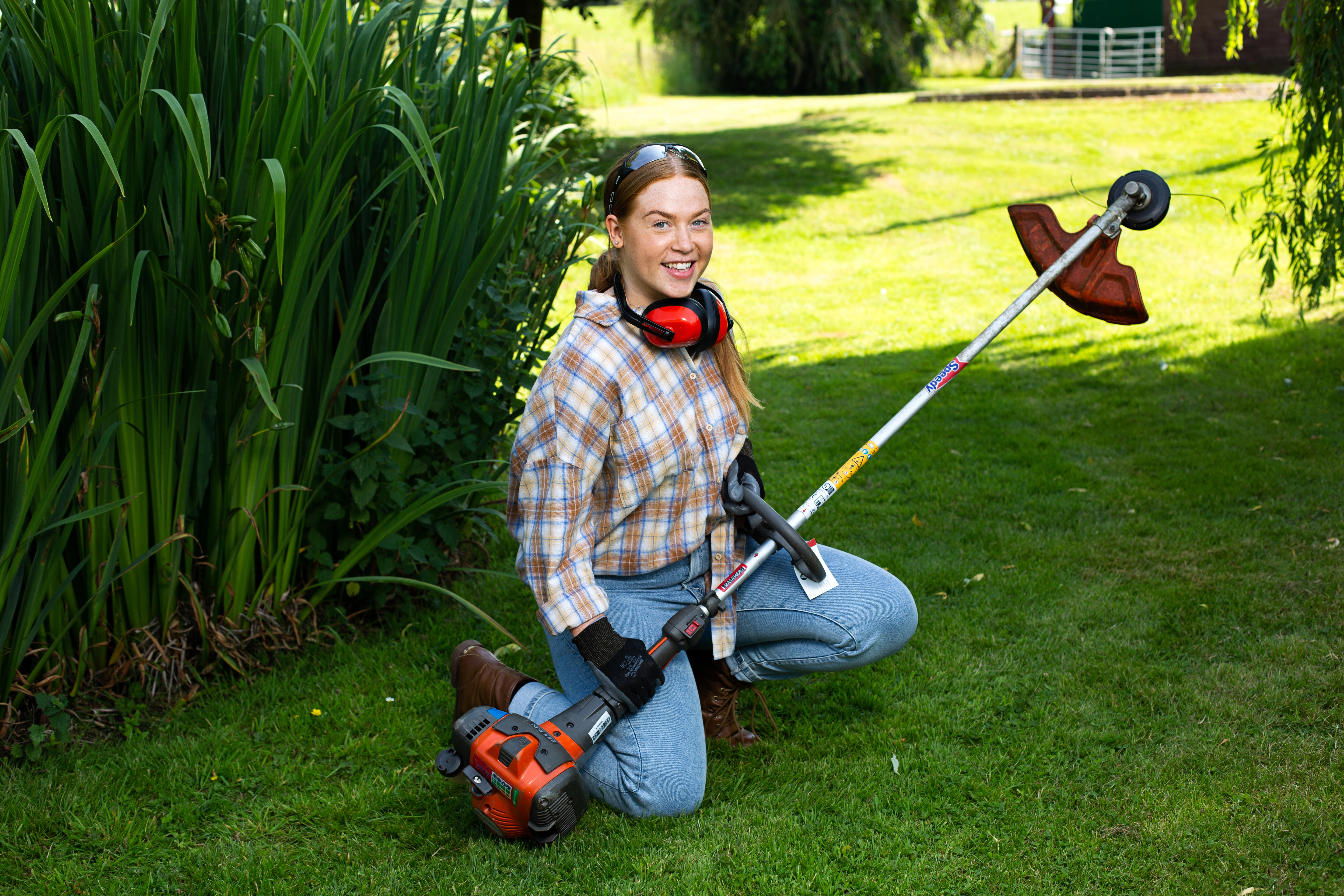 a girl using the grass trimmer to do landscaping