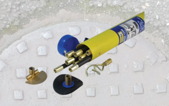Drain cleaning kit with yellow tube and multiple brass fittings displayed on a concrete surface.