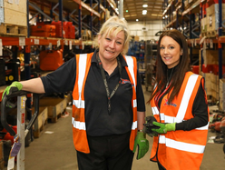 2 speedy staff standing in a warehouse surrounded by equipment