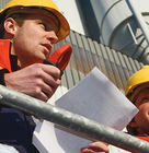 Construction workers wearing safety helmets and high-visibility jackets communicating on-site.