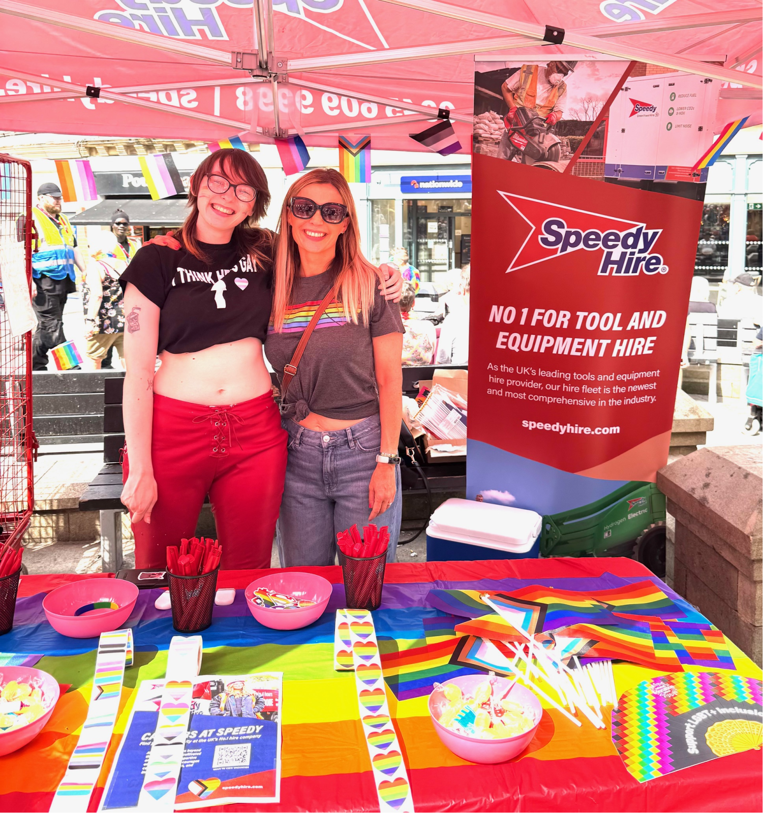 2 speedy staff standing behind a table of LGBT+ supporting materials