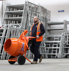 a Speedy worker pushing a cement mixer inside a warehouse
