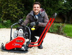a person sitting next to a plate compactor in the garden