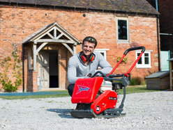 a man sitting next to a wacker plate while building the driveway