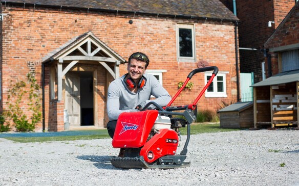 a man sitting next to a wacker plate while building the driveway