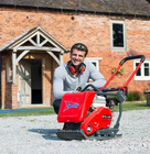 a man sitting next to a wacker plate while building the driveway