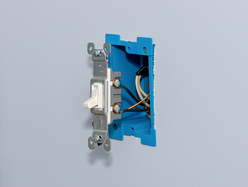 Partially installed light switch fitted into a blue electrical wall box.