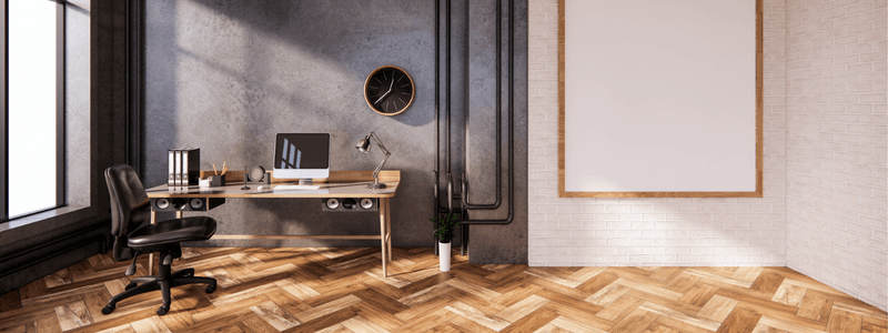 Bright, spacious modern office room with a wooden desk, computer, and herringbone flooring.