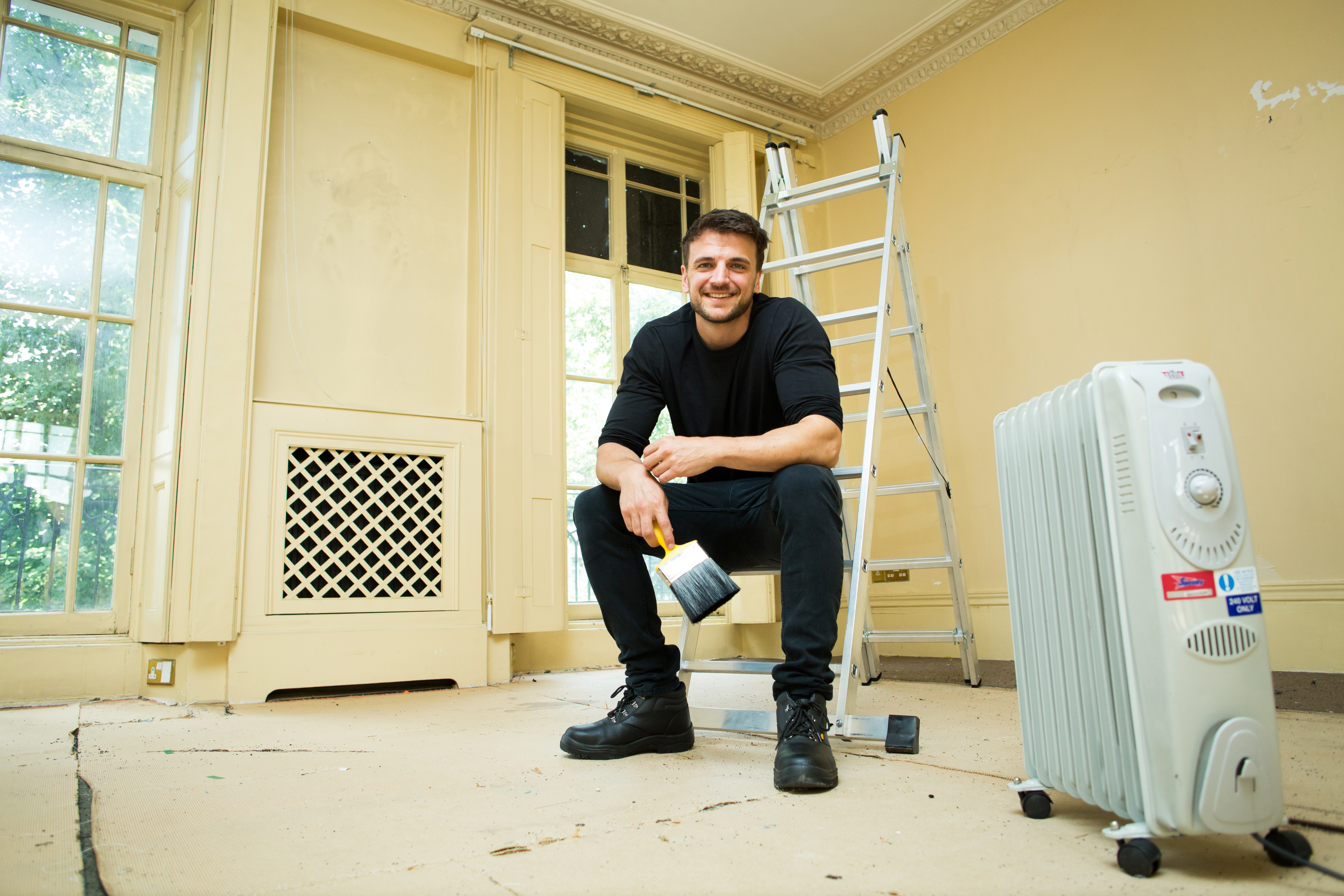 An oil‑filled radiator heater positioned on the floor of a room being renovated