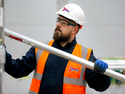 Worker wearing Speedy-branded safety gear assembling aluminum scaffold frame indoors.